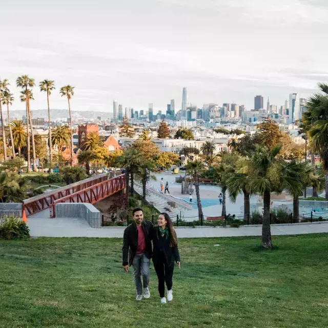 Un couple se dirige vers la caméra avec Dolores 由k et la Skyline 贝博体彩app derrière eux.